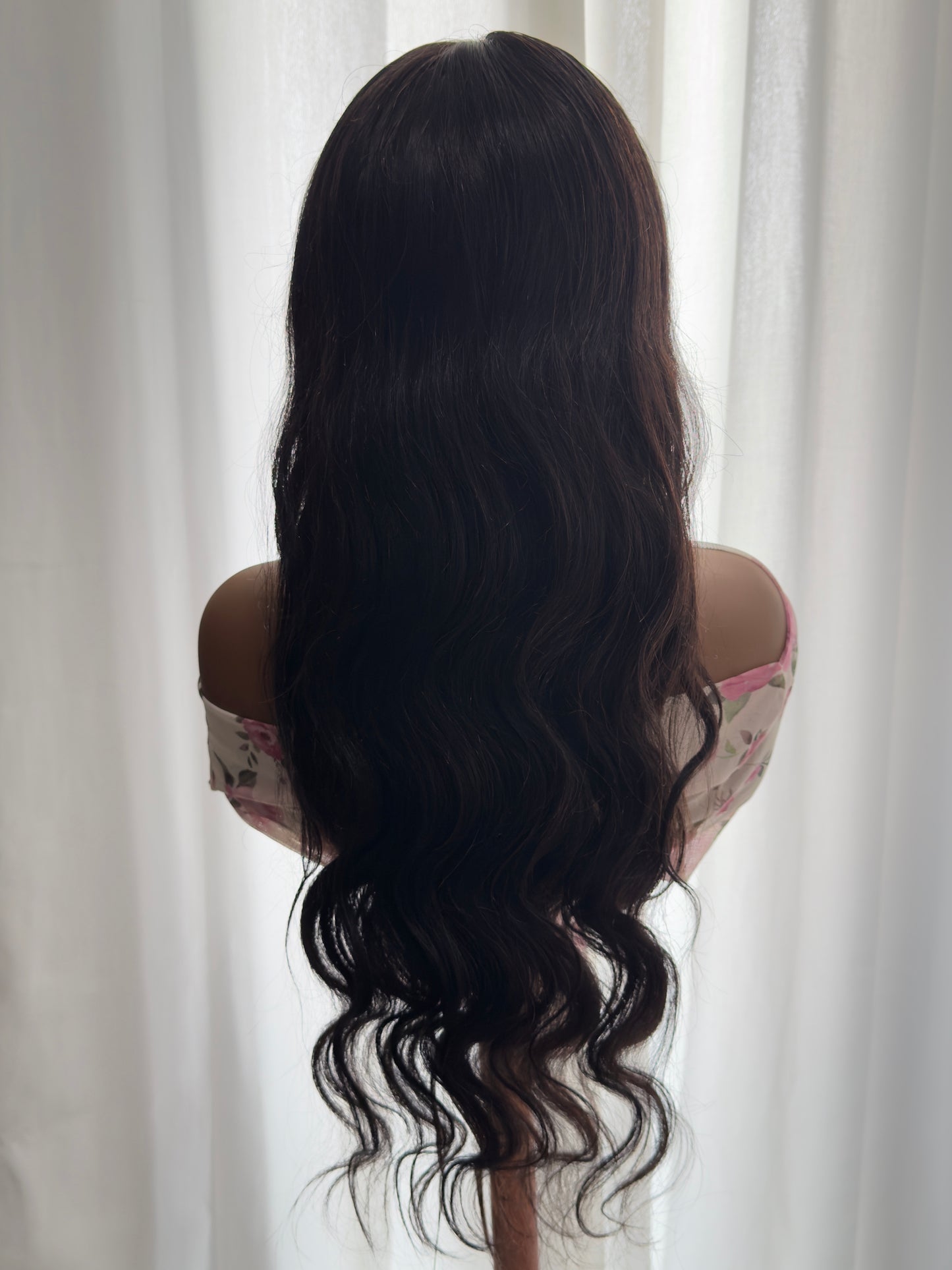 Person with long, wavy hair flowing freely against a neutral background