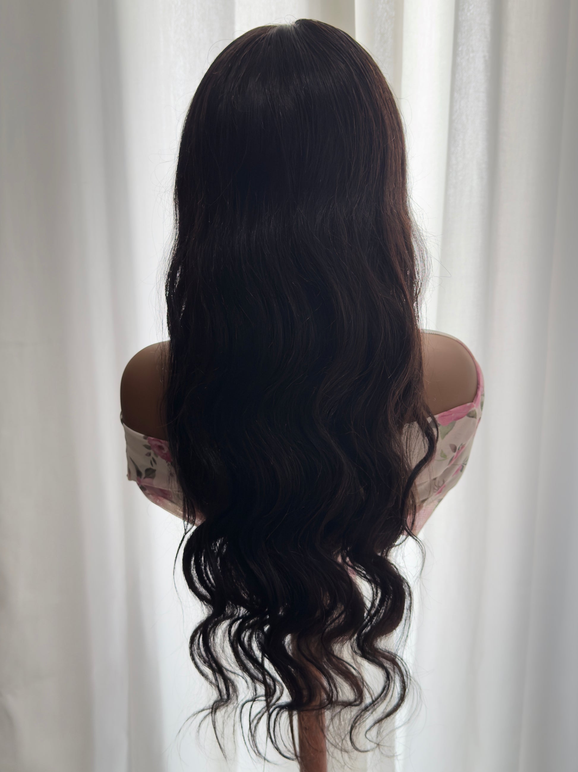 Person with long, wavy hair flowing freely against a neutral background